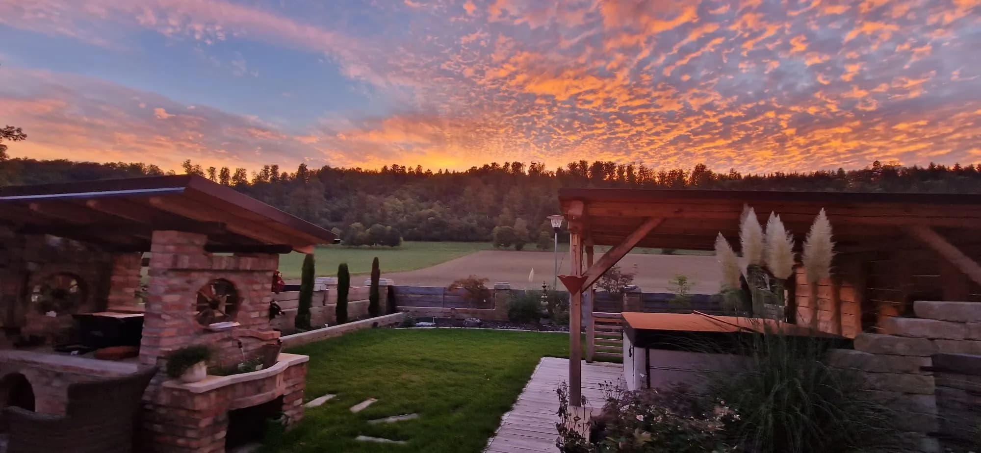 Angelegter Garten mit Terrasse und Pergola im Abendlicht