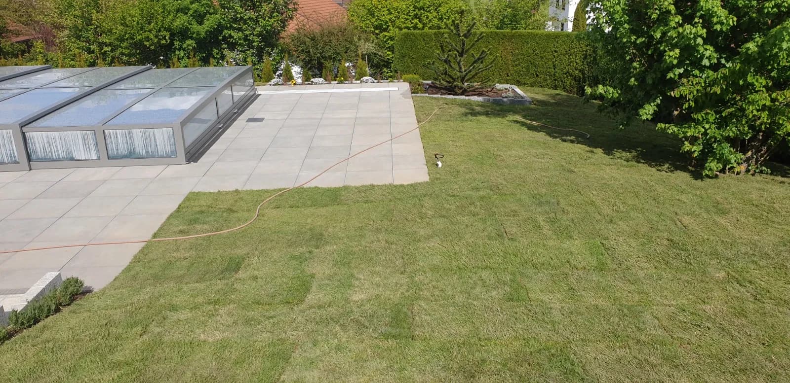 Gartenschaufel mit Erde vor einem blühenden Beet